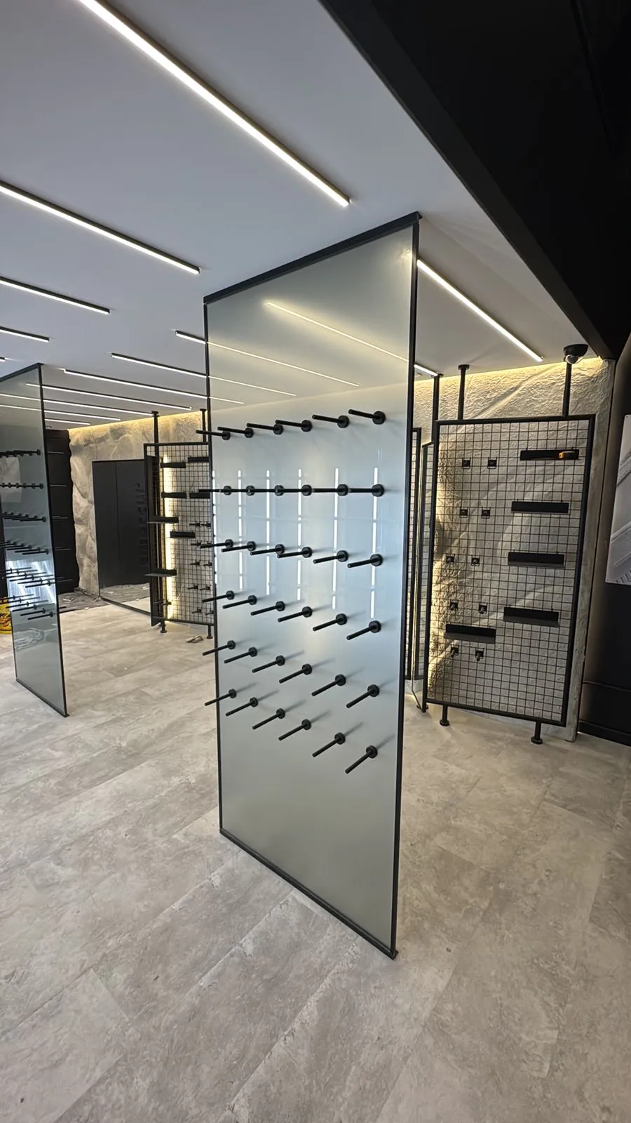 Showroom de acabados con iluminación LED lineal empotrada en cielo raso y pisos en porcelanato gris