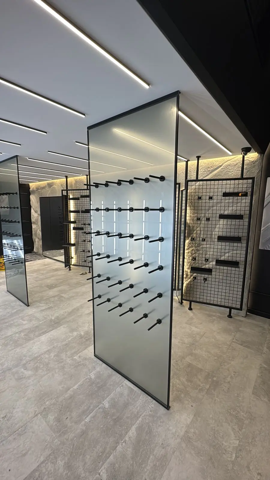 Showroom de acabados con iluminación LED lineal empotrada en cielo raso y pisos en porcelanato gris